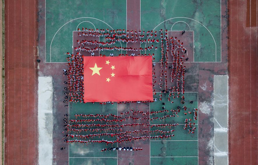 挥舞着手中的小红旗,歌声嘹亮,现场组成的一面巨大五星红旗震撼人心