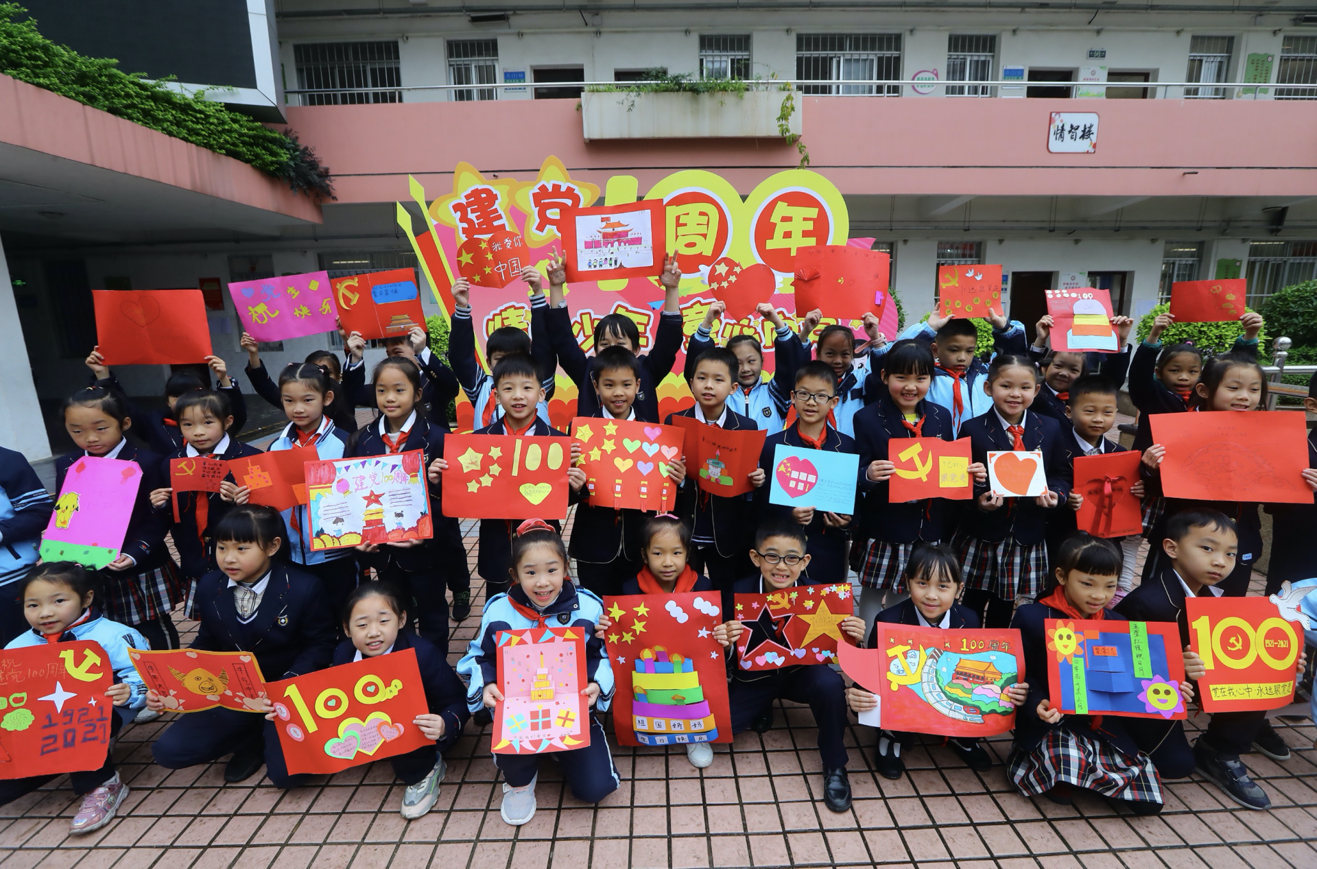 热情高涨的同学们在操场上举起自己精心制作的"献礼建党100周年"祝愿