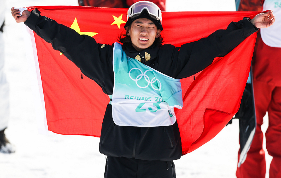 苏翊鸣夺金后披国旗庆祝15日,北京冬奥会单板滑雪男子大跳台比赛,中国