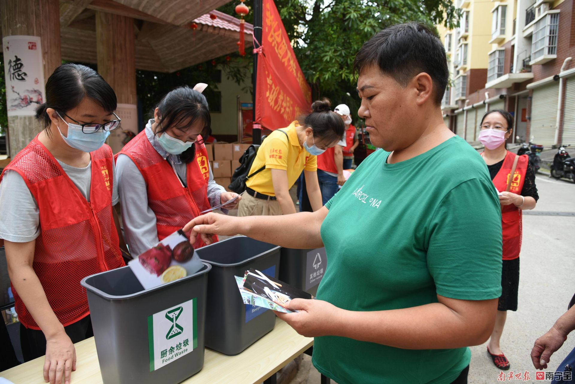 图为南宁晚报党员志愿者在垃圾分类互动游戏摊点为现场居民服务